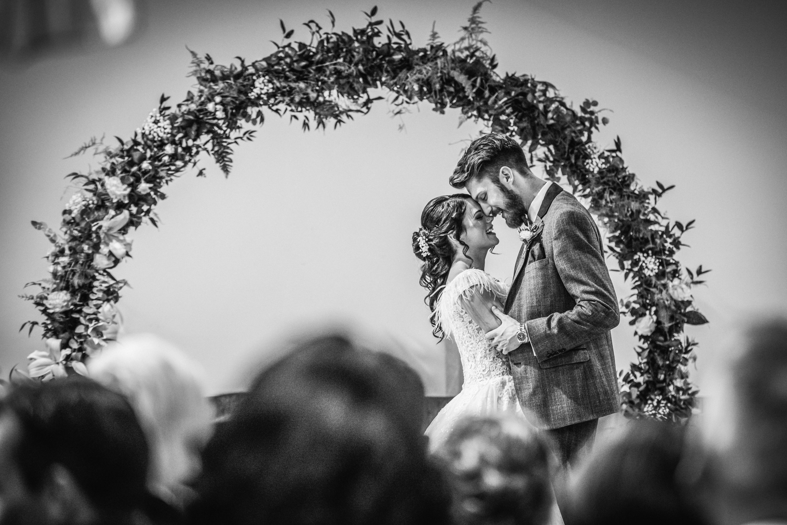 Couple standing under floral arch during wedding ceremony